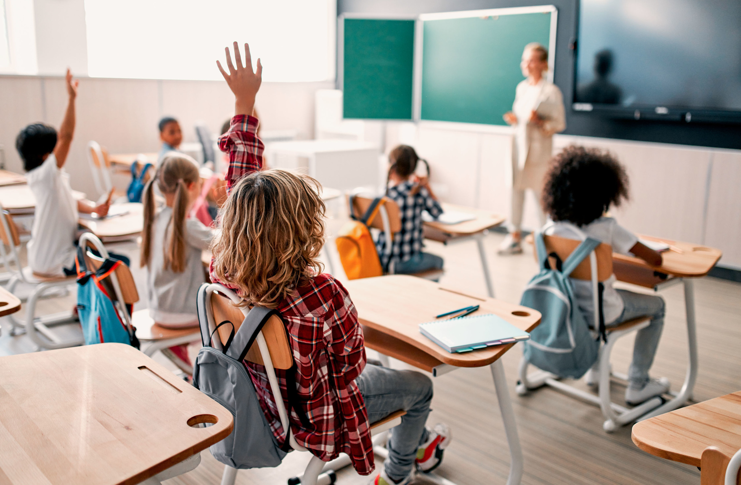 Children in a class raising hands
