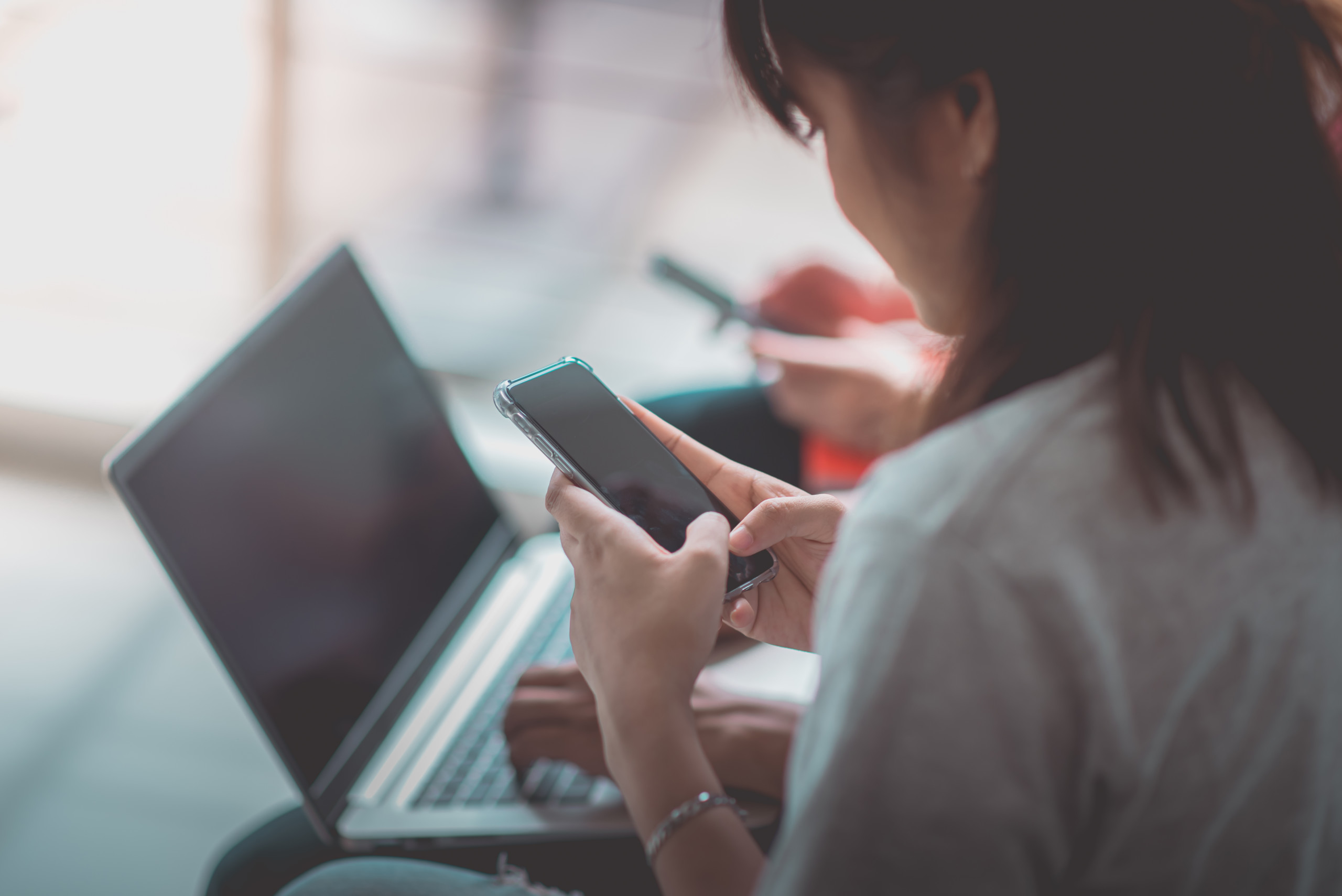 Sitzende Frau mit einem Smartphone in den Händen
