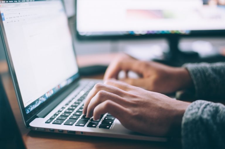 Nahaufnahme eines Laptops mit tippenden Händen