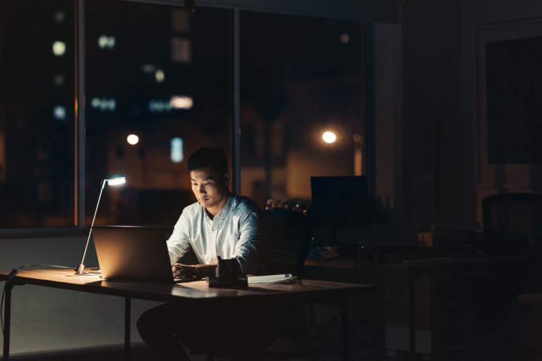 Young Asian businessman working overtime in a dark office