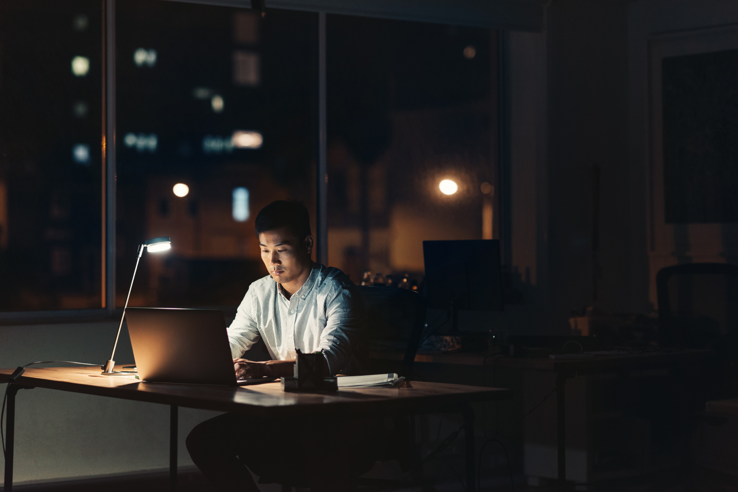 Young Asian businessman working overtime in a dark office