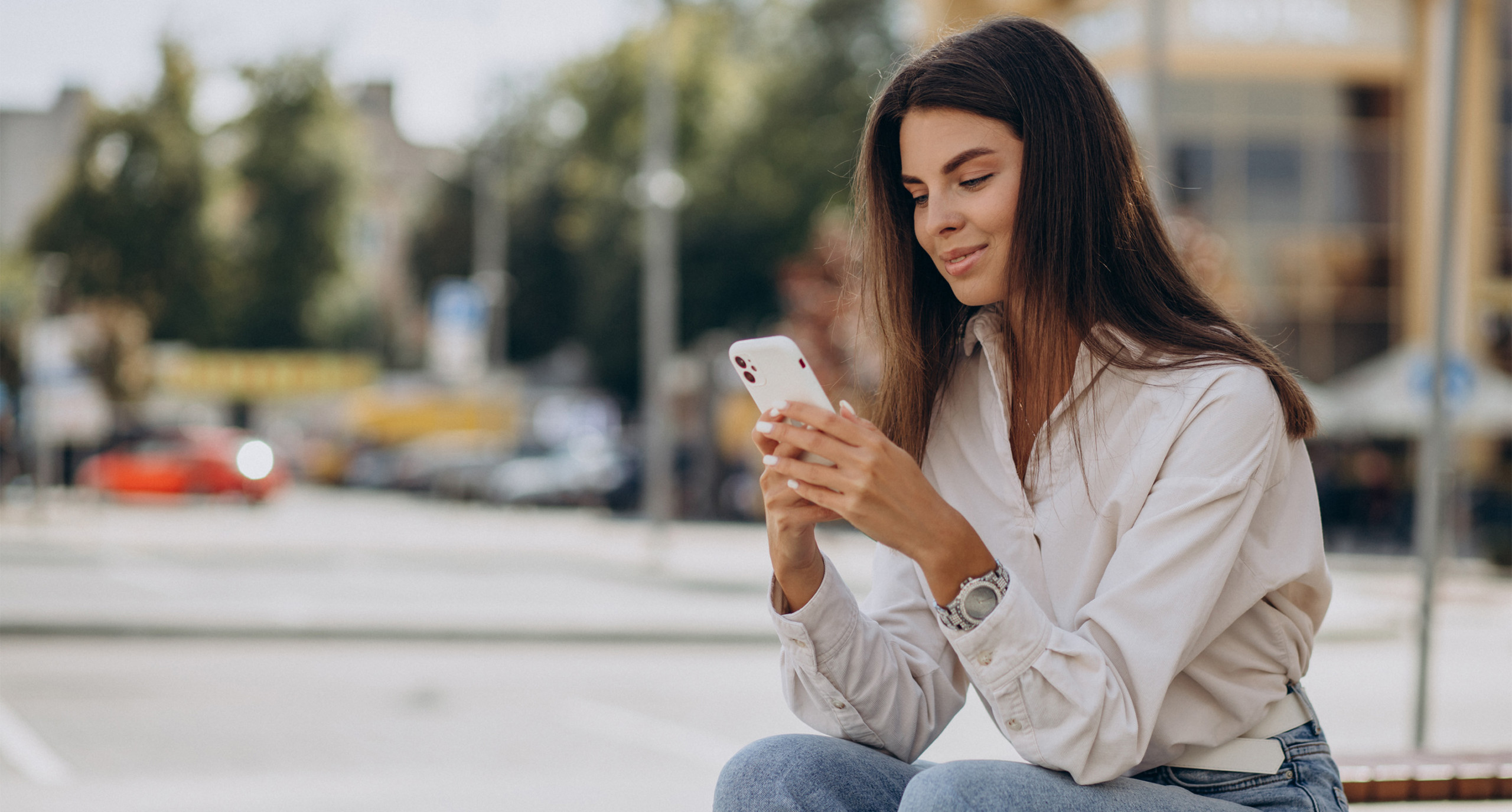 young woman sitting outside using mobile