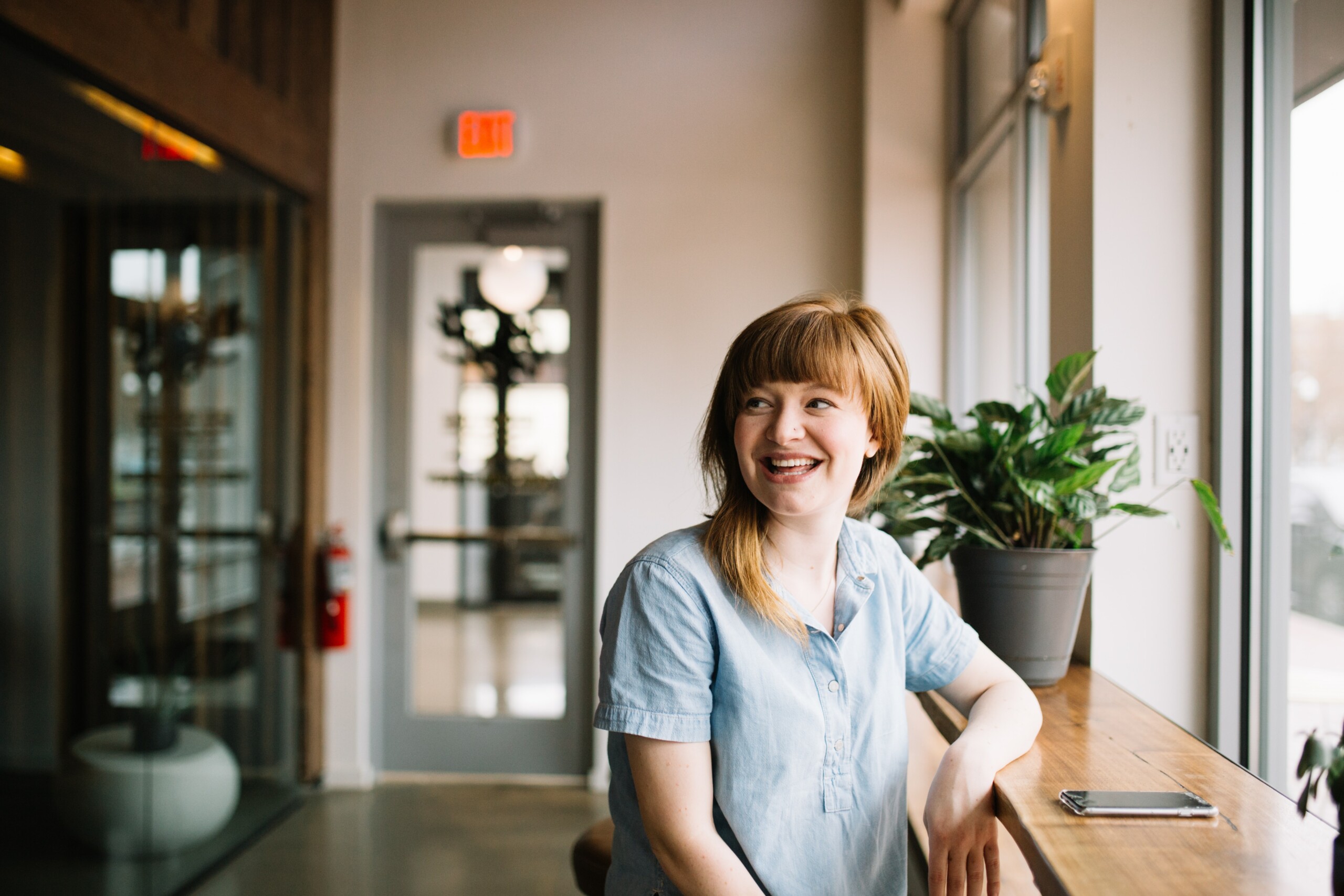 Woman sitting in an office and smiling, phone on the table