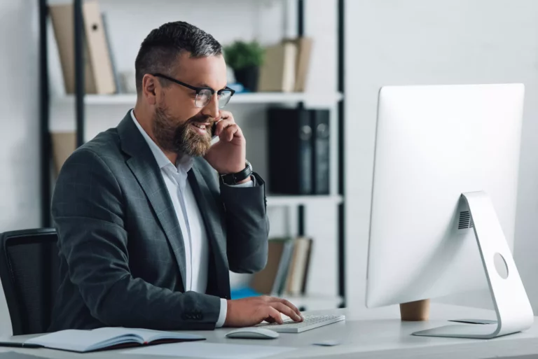 Man using a computer and talking on phone